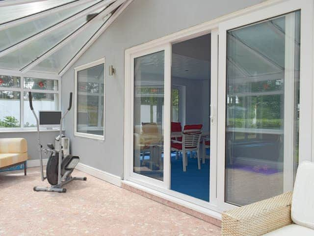 Patio doors connect the swimming pool to the conservatory | Buttercup Cottage, Halsall, near Ormskirk