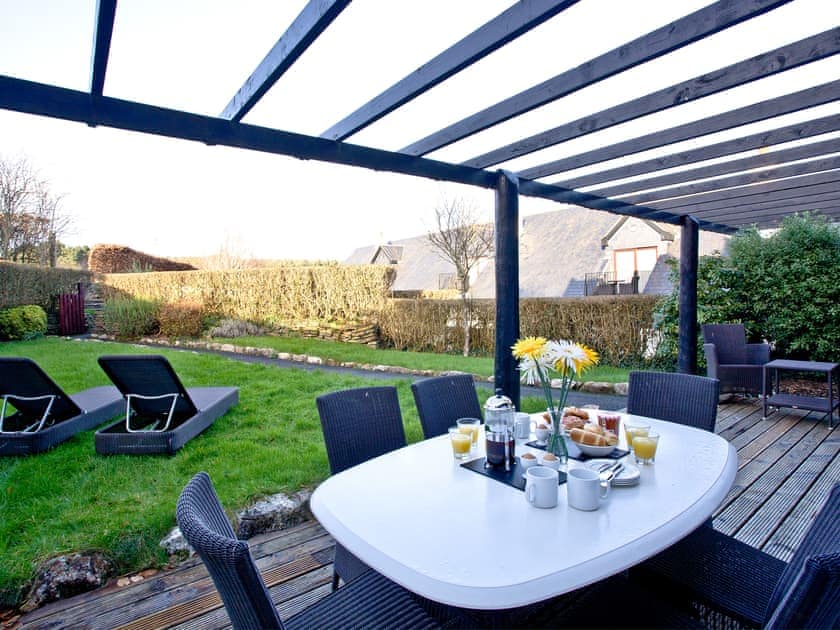 Decked area with table and chairs overlooking the garden | Orchid - Woodland Retreat, Wadebridge