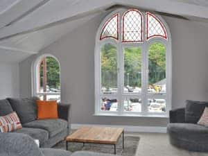 The huge floor to ceiling arched window in the lving area affords views of the river  | St Monicas, Fowey