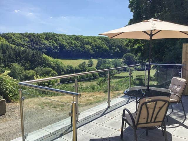 Patio with table and chairs overlooking the beautiful Cornish landscape | Orchard Close - Sanctuary Farm Cottages, Morwenstow, near Bude