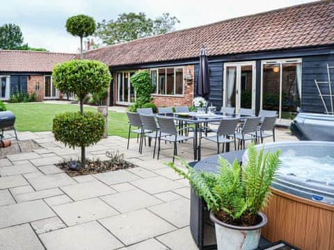 Enclosed courtyard. The hot tub can take eight people easily.  There are also outdoor sofas a small barbecue and a dining table for 12. | Lodge Farm Barn, South Walsham