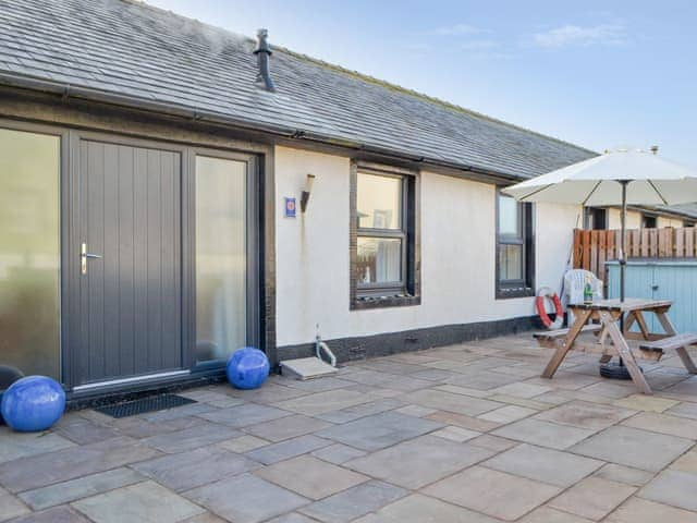 Paved patio area with outdoor furniture | Porthole Cottage, Allonby, near Maryport