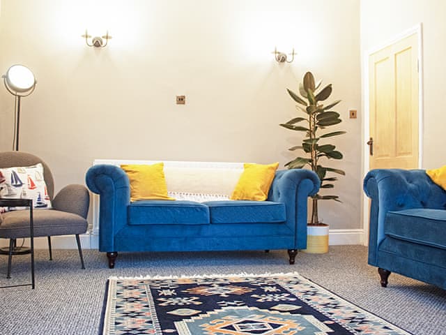 Second living space with cosy soft velvet chesterfield sofas with blankets and cushions to help you relax. | Captain’s Cottage, Shanklin