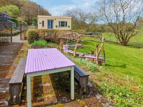 outdoor dining area, and fire pit with seating area. Rosie in the background which is the sleeping area. | Rosie - Tanyrallt Holidays Lets, Llanybydder, near Lampeter