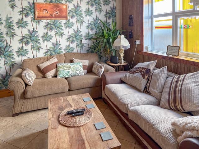Jungle room tv area with two comfortable couches | Lilac Villa, Skegness