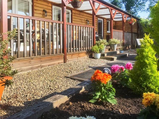 Veranda and private outdoor patio, facing west at rear of lodge | Cedar Lodge, Cowbeech, near Hailsham