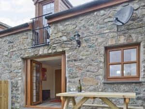 Outdoor eating area and French door entrance to cottage | Ysgubor Myfi - Trehwfa Cottages, Bodedern, near Holyhead