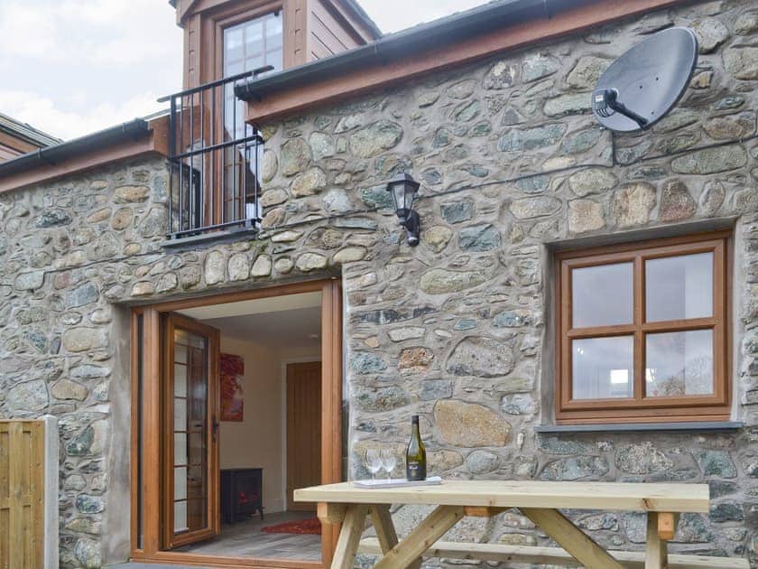 Outdoor eating area and French door entrance to cottage | Ysgubor Myfi - Trehwfa Cottages, Bodedern, near Holyhead