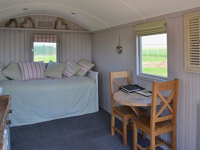 Compact table and chairs and sofa that converts to kingsize double bed | The Lincoln Longwool - West Hale Shepherd&rsquo;s Huts, Burton Fleming, near Filey