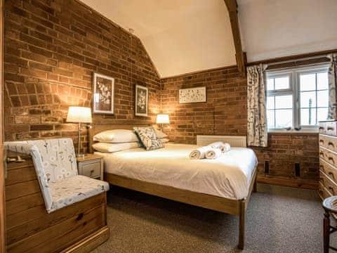 Double bedroom with exposed brick walls and sloping ceiling | Yarlington Mill - The Old Kennels Holidays, Ledbury