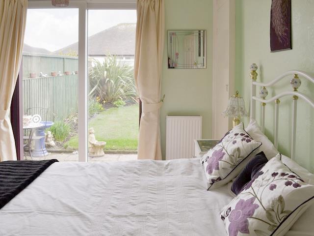 Comfortable double bedroom with patio doors to garden | Rossall Beach Cottage, Rossall, near Thornton-Cleveleys.