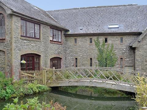 Charming wooden footbridge over the millpond | Bridge House - Lower North Radworthy Cottages, Heasley Mill, near South Molton