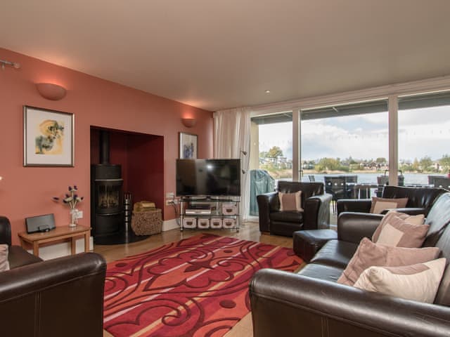 Open plan living space with wood burner & patio doors leading to decking area | The Augusta House, Somerford Keynes