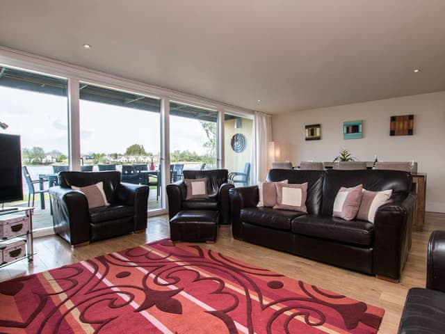 Living/dining space with patio doors leading to decking area | The Augusta House, Somerford Keynes