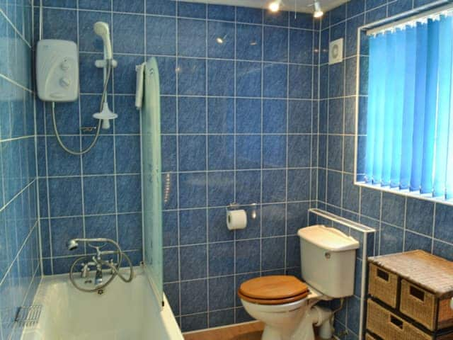 Bathroom featuring shower over bath, toilet and heated towel rail | Stable End - Peregrine Hall Cottages, Lostwithiel