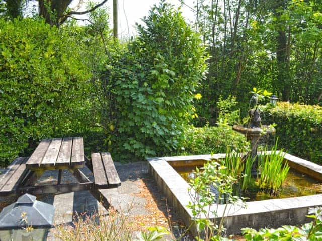 Delightful outdoor sitting area with pond (unfenced) within grounds | Stable End - Peregrine Hall Cottages, Lostwithiel