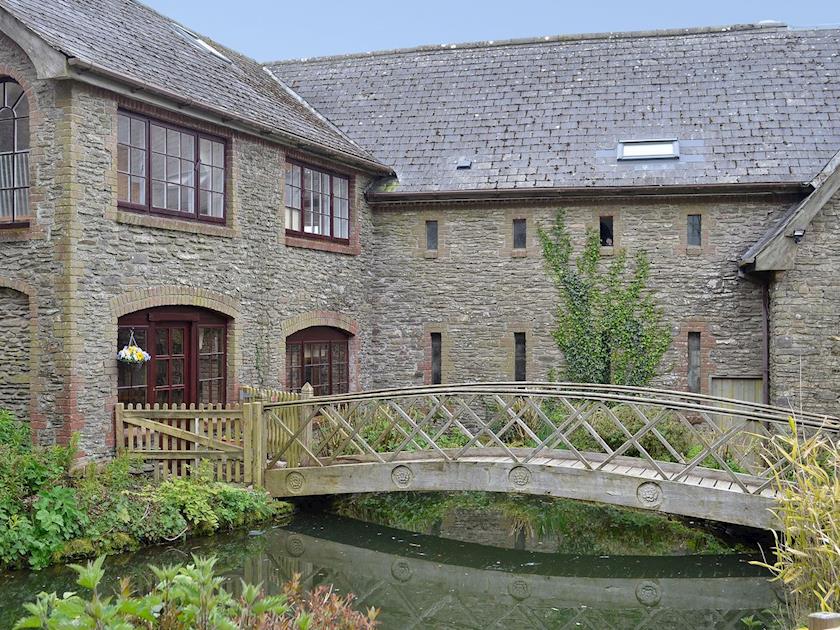 Charming wooden footbridge over the millpond | Bridge House - Lower North Radworthy Cottages, Heasley Mill, near South Molton