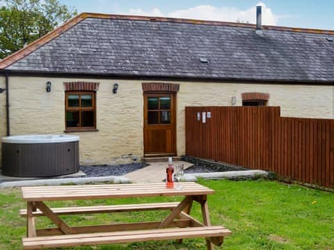 Enclosed lawned garden with sitting-out area, garden furniture and private hot tub | Yr Hen Stabal - Bronallt Barns, Llanynghenedl, near Holyhead