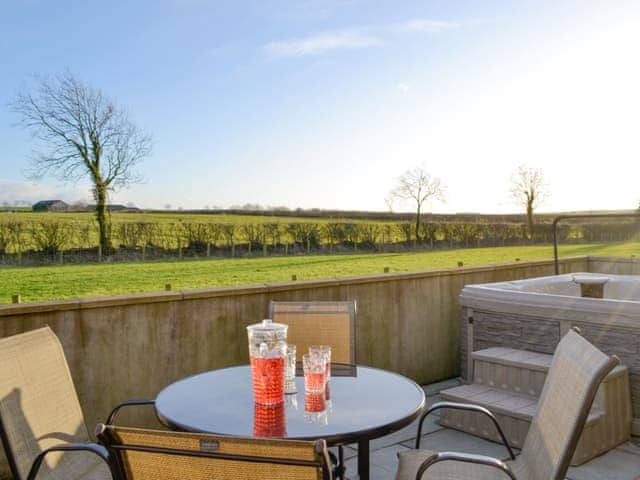 Enclosed patio with outdoor seating and hot tub | Little Meadow - West House Farm, Dearham, near Maryport