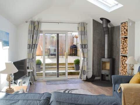 Cosy lounge area with wood burner and patio doors leading to the decking area | Little Tregarthen, Padstow