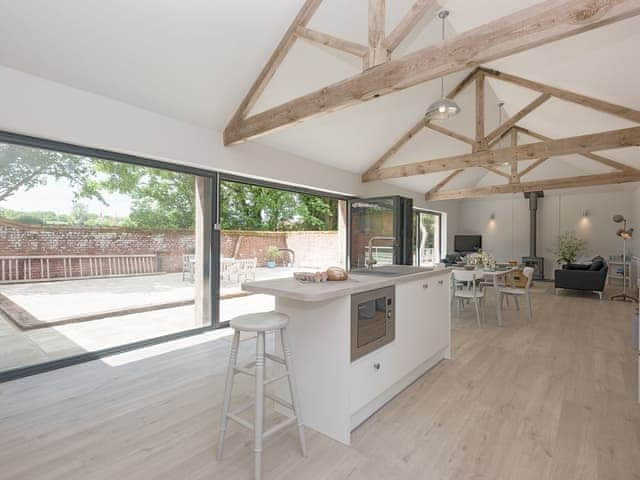 Modern open-plan living space with exposed wooden trusses | The Cowshed, Reepham