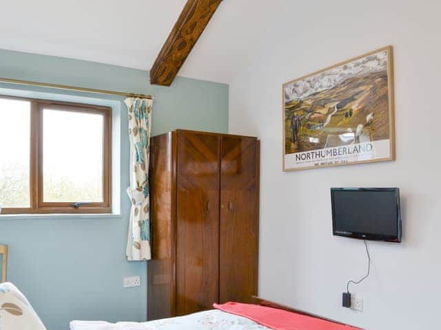 Wall mounted TV in double bedroom and carved wooden beams | Shepherdskirk - Wide Sky Cottages, Lowick, near Berwick-on-Tweed