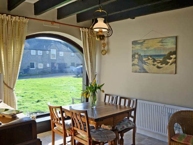 Quaint dining area looking out of arched window | Sandsedge Cottage, Druridge Bay