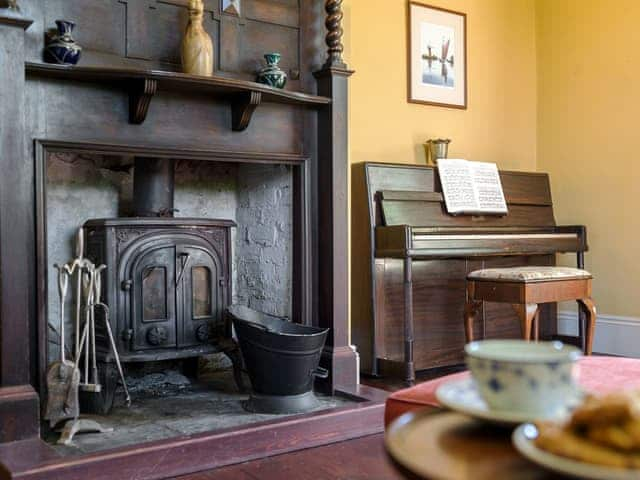 Wood burner and piano in second living room | Tilney Hall, Kings Lynn