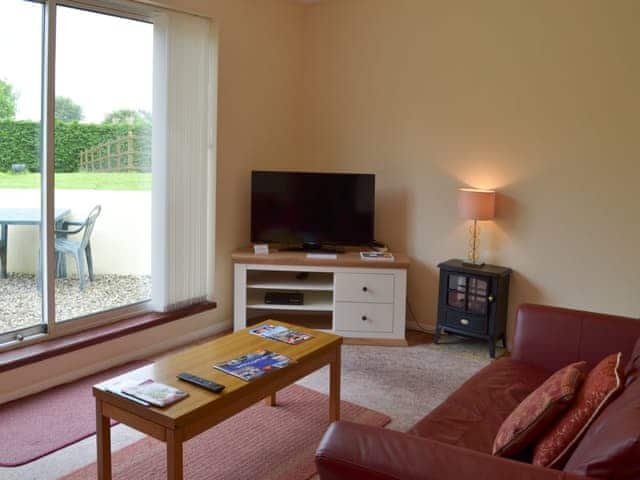 Spacious living room with patio doors to sitting-out-area | Honeysuckle Bungalow - Devon Palms, Maidencombe, near Torquay