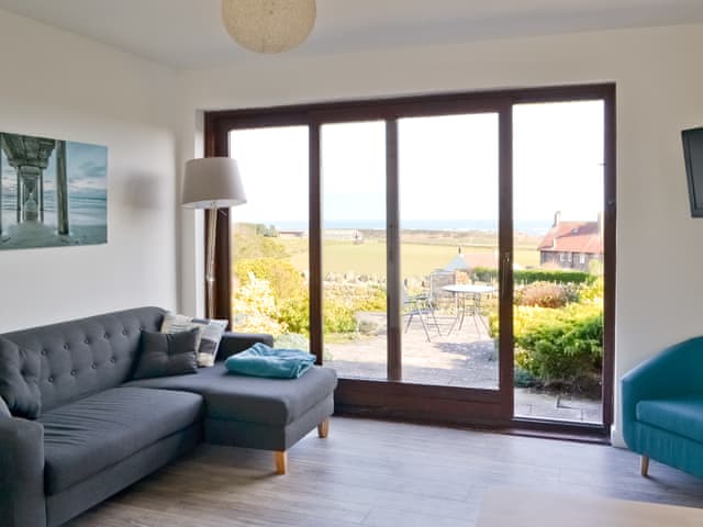Light and airy lounge area with sliding patio doors | Eider Cottage, Embleton