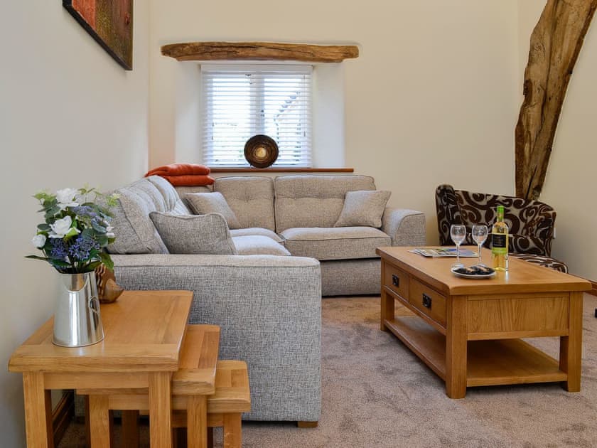 Welcoming living area with exposed woodwork and wood burner | Cruck Barn - Plas Iwrwg, Maenan, near Llanrwst