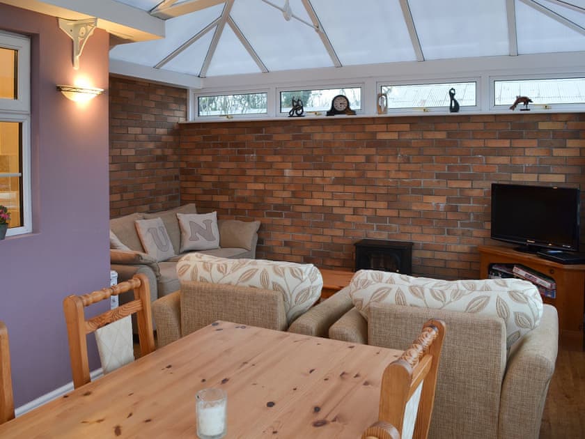 Dining area and living room with exposed brickwork | Ty Canol, Brynteg, Anglesey