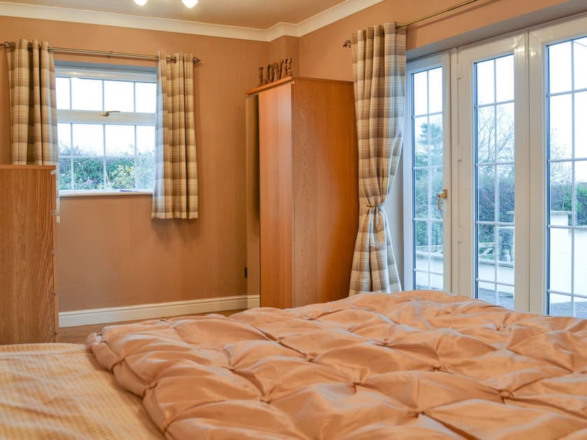 Cosy double bedroom with doors to the outside area | Ty Canol, Brynteg, Anglesey
