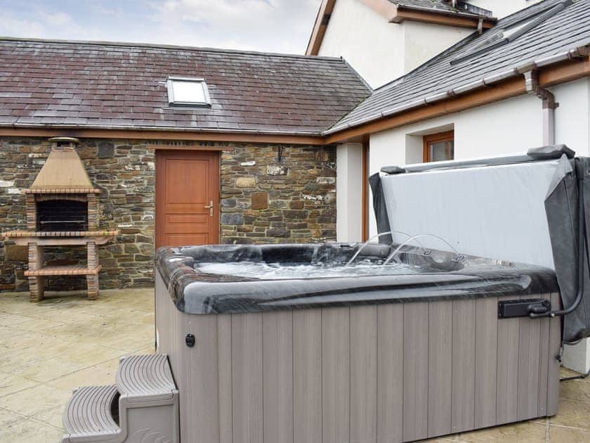 Luxurious hot tub on the paved patio | The Farmhouse - Ffynnonmeredydd Cottages, Mydroilyn, near Aberaeron