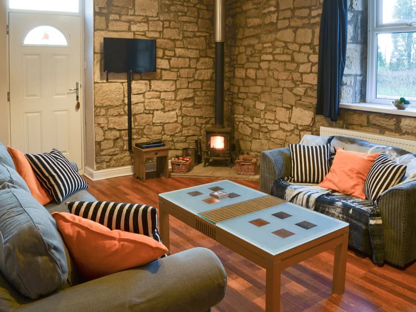 Charming living area with exposed stone walls and wood burner | Stable Cottage - Railway Cottages, Acklington, near Amble