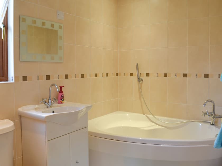 En-suite bathroom with shower attachment over the corner bath | Yorkshire Rose Holiday Lodge, Sewerby, near Bridlington