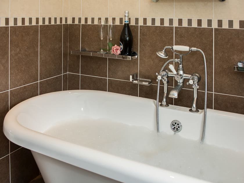 Wonderful romantic bathroom with roll top bath and telephone style shower attachment | The Coach House, Fremington, near Richmond
