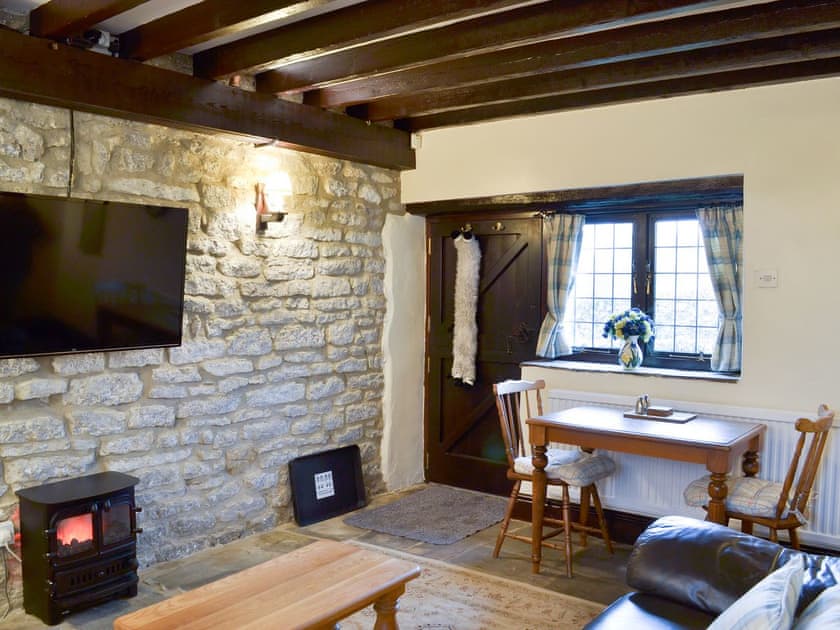 Cosy living area with exposed stone wall | Dale House Farm Cottage, Monyash, near Bakewell