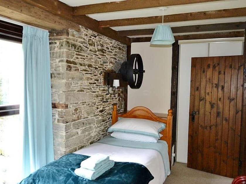 The twin bedroom has large floor to ceiling windows looking out across the garden | Mill Cottage, Fowey