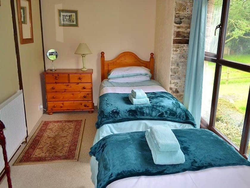 The twin bedroom has large floor to ceiling windows looking out across the garden | Mill Cottage, Fowey