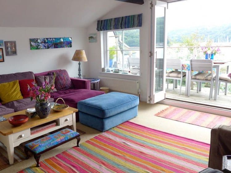 Colourful sitting room with patio doors leading to the large balcony | Polbathic, Fowey