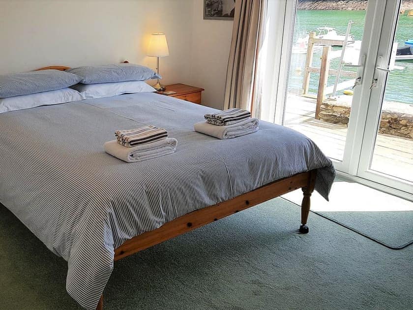 Double bedroom with  French doors leading out onto a small decked patio area with lovely views of the river | Tarquins, Fowey