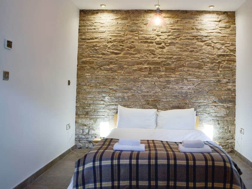 Double bedded room with feature stone wall | Bwythn Y Saer, Plas Cilybebyll, near Pontardawe