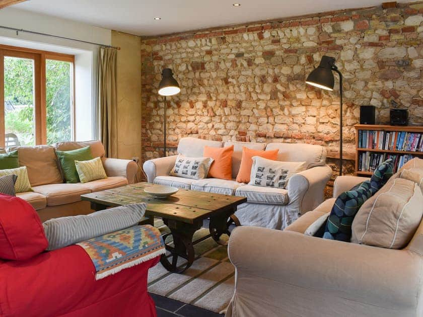 Cosy and comfortable living room with feature stone wall | The Granary, Oxborough