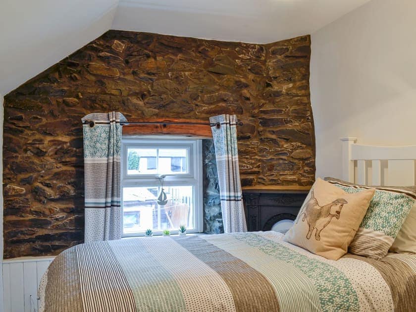 Bedroom with exposed stone wall | Noddfa Cottage, Llanfairtalhaiarn, near Abergele