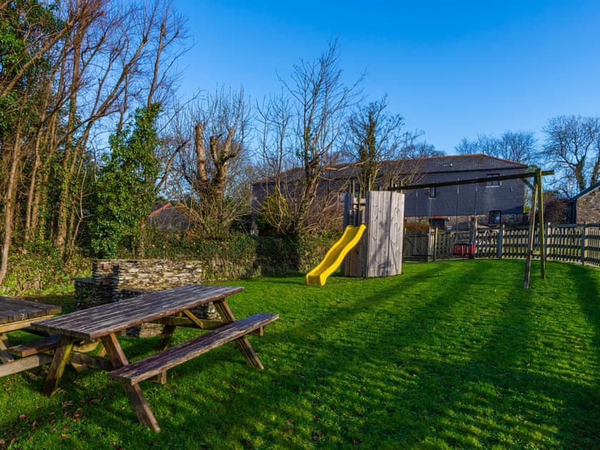 Lawned area with children’s play equipment | Dairy Cottage, Fowey