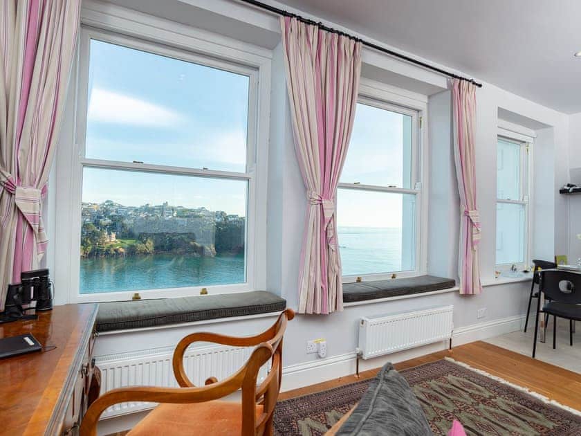 The main living area with oak flooring is open plan and comfortably furnished with retro 1930’s style furniture | St Catherines Court No 4, Fowey