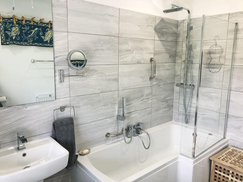 Bathroom with shower over P-shaped bath | May Escape, Heswall, near Liverpool
