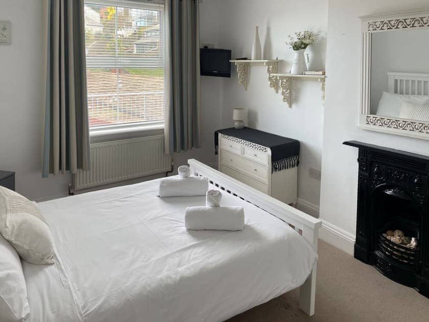 Double bedroom with feature fireplace and dressing table | Evelyn Cottage, Dartmouth