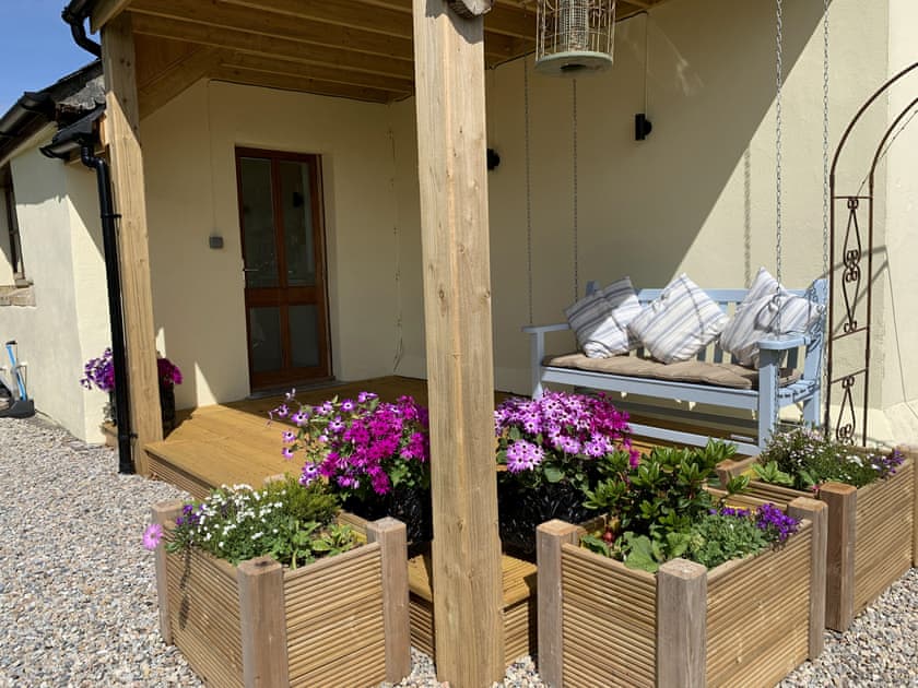 Peaceful veranda with swing seat and dining area | The Headmaster’s Cottage, South Hill, near Tamar Valley